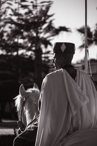 Black and white image of a formal guard riding a horse, exuding dignity and tradition.