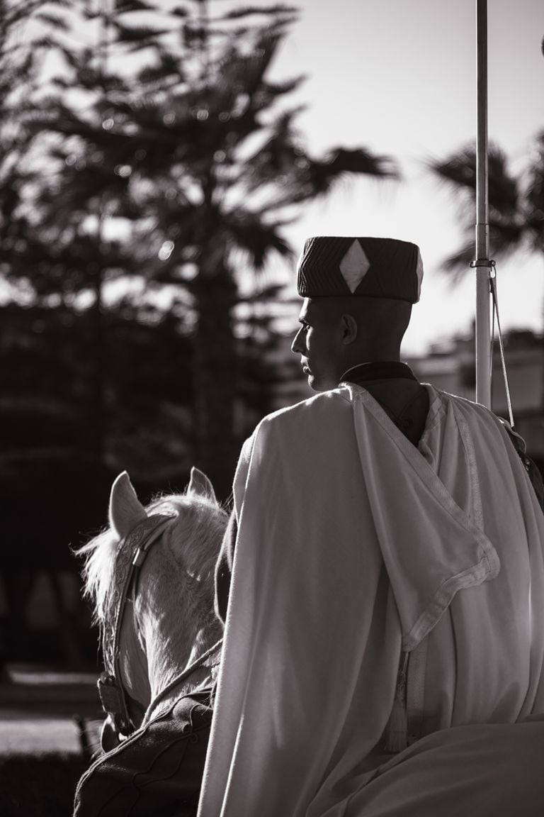 Black and white image of a formal guard riding a horse, exuding dignity and tradition.